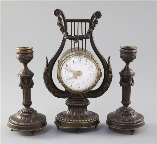 An early 20th century French patinated bronze garniture, clock 21.5cm. candlesticks 15cm.